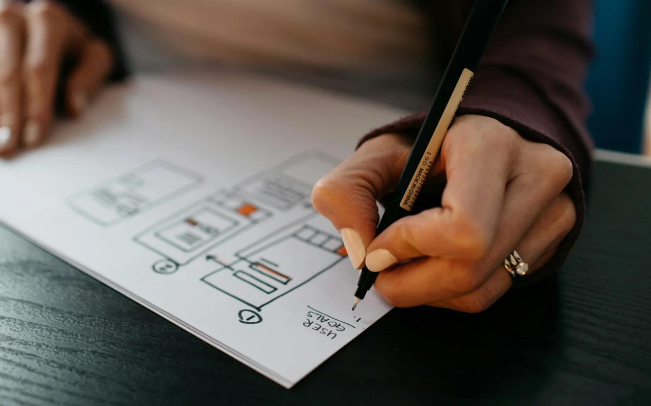 Hands sketching a website wireframe on paper