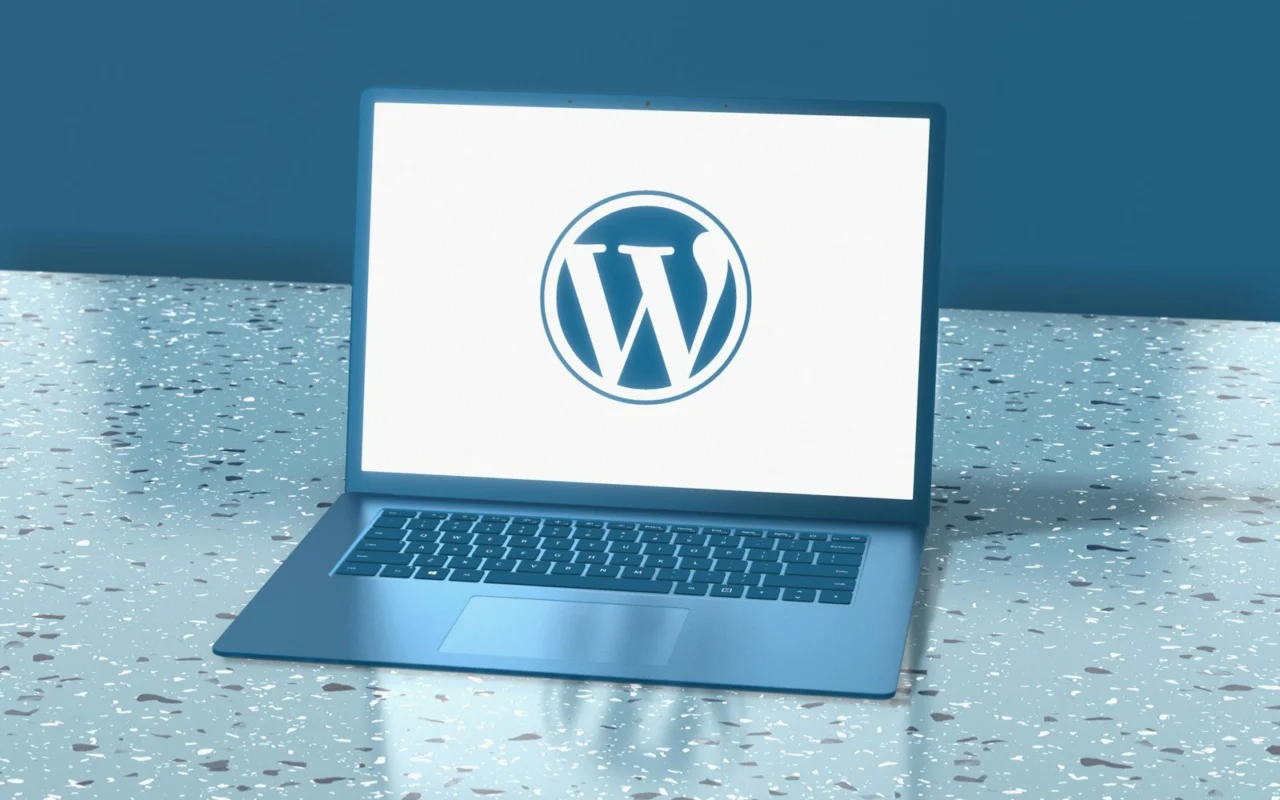 Laptop showing the WordPress logo on a blue desk